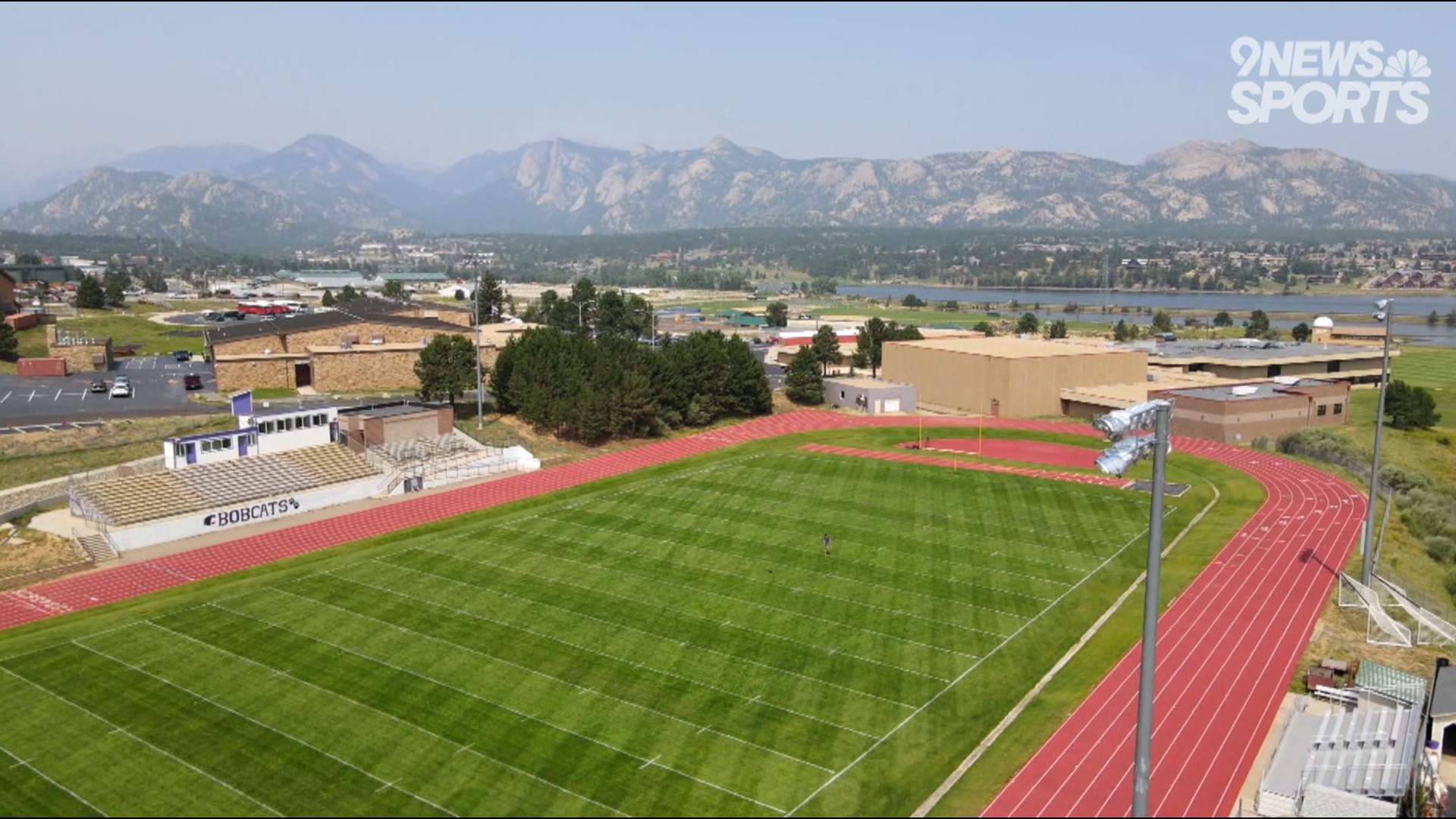 The football field at Estes Park is surrounded by mountains and a lake.