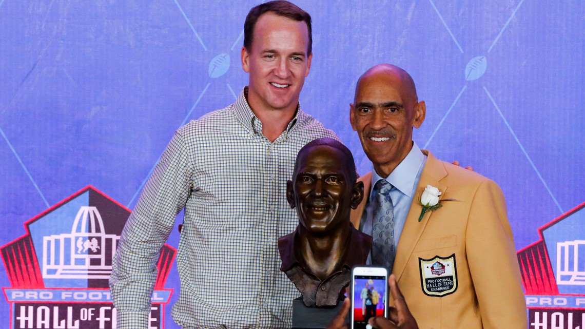 Peyton Manning in his new Broncos jersey flanked by Eli Manning