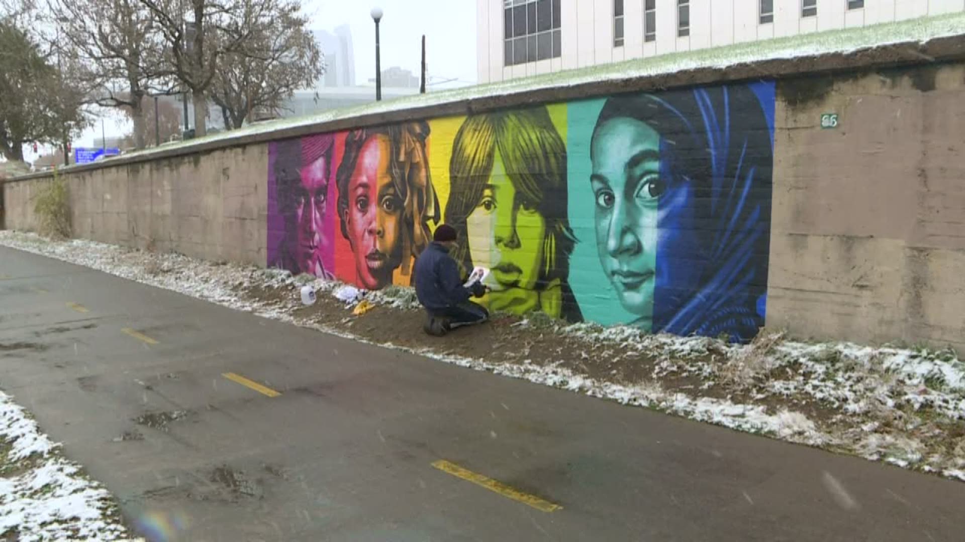 Rafael Blanco is painting a mural on the Cherry Creek Bike Path. He says, he likes meeting the people who are going to live with the mural and seeing it every day.