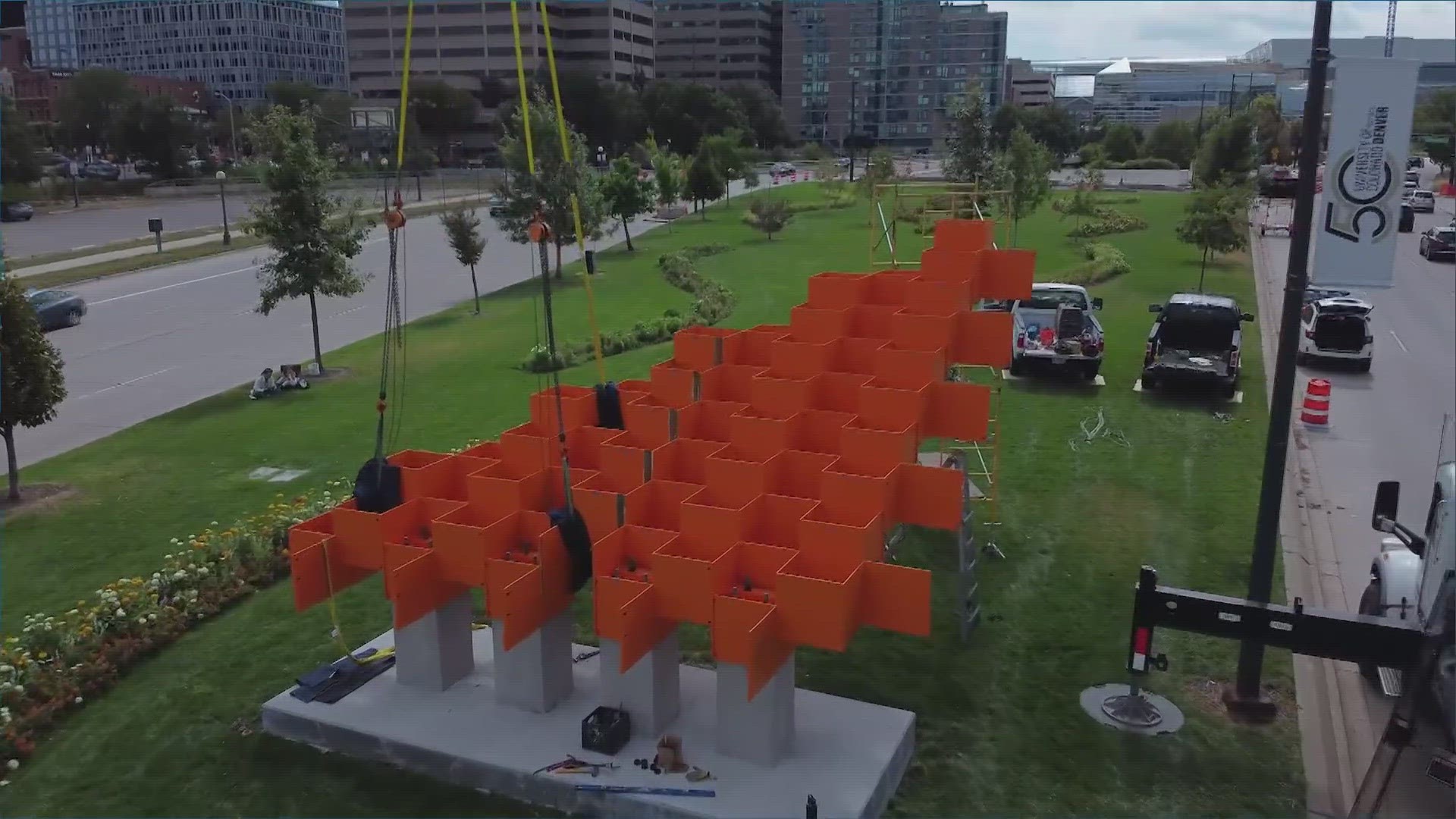 An abstract sculpture with orange steel and blue plexiglass is back on Speer Boulevard.