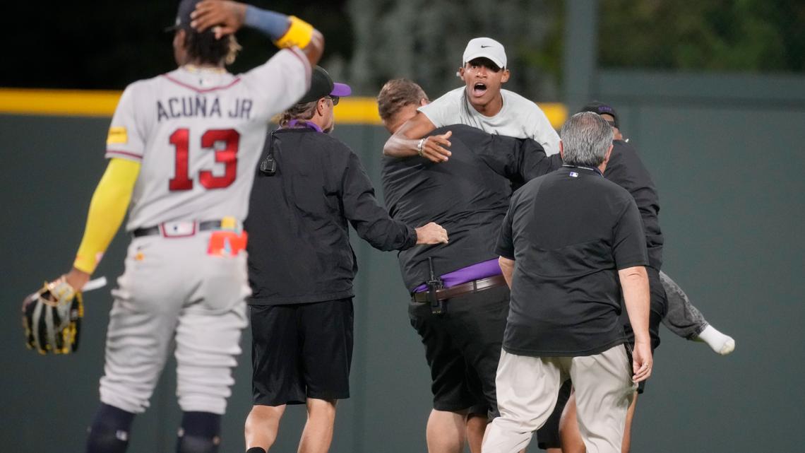 Atlanta Braves' Ronald Acuña Jr. knocked to the ground after two fans run  onto Coors Field