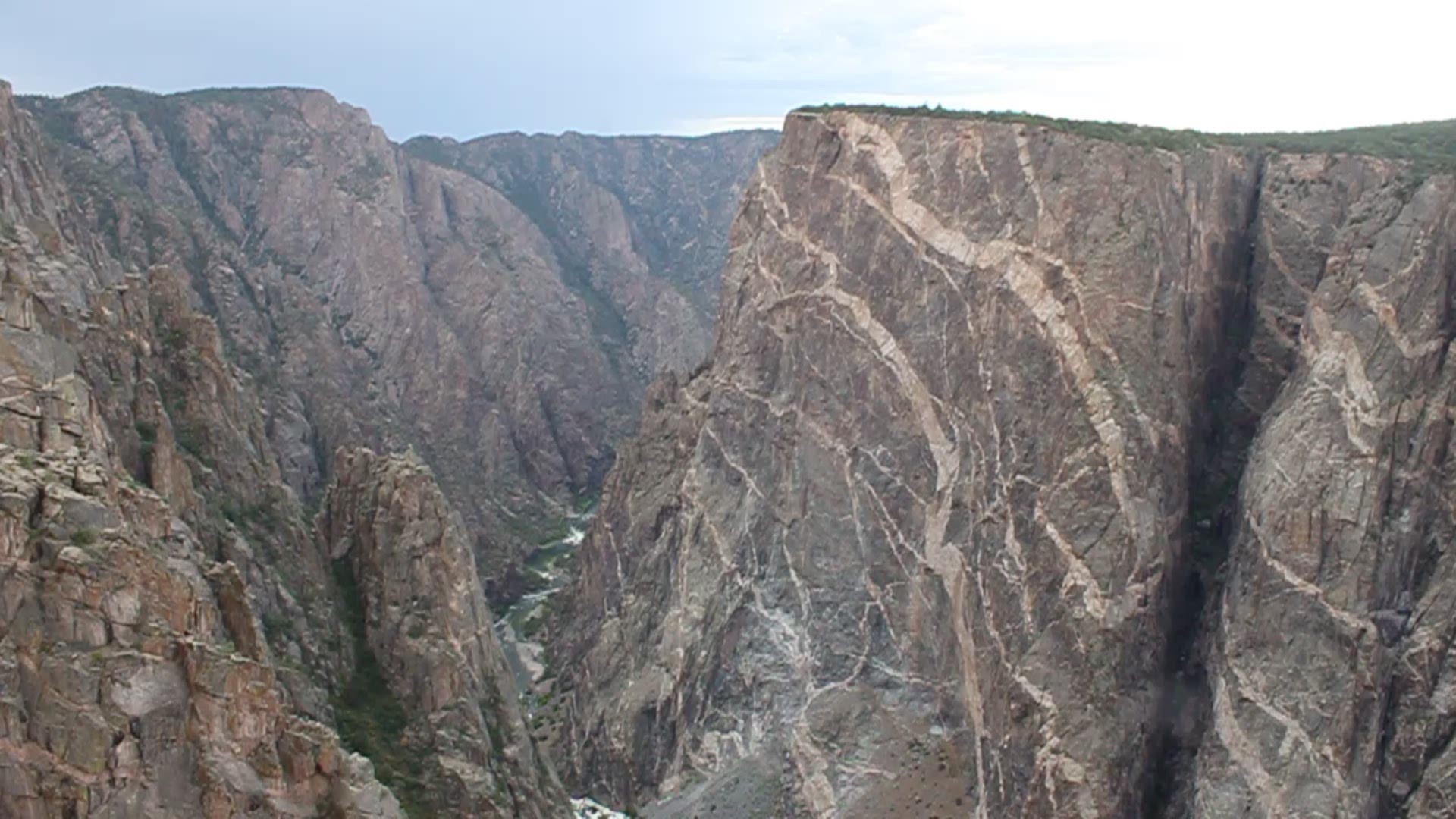 The view from the overlook at one of the most iconic locations inside Black Canyon of the Gunnison National Park in Colorado. It is more than 2,200 feet from the top of The Painted Wall down to the Gunnison River on the canyon floor.