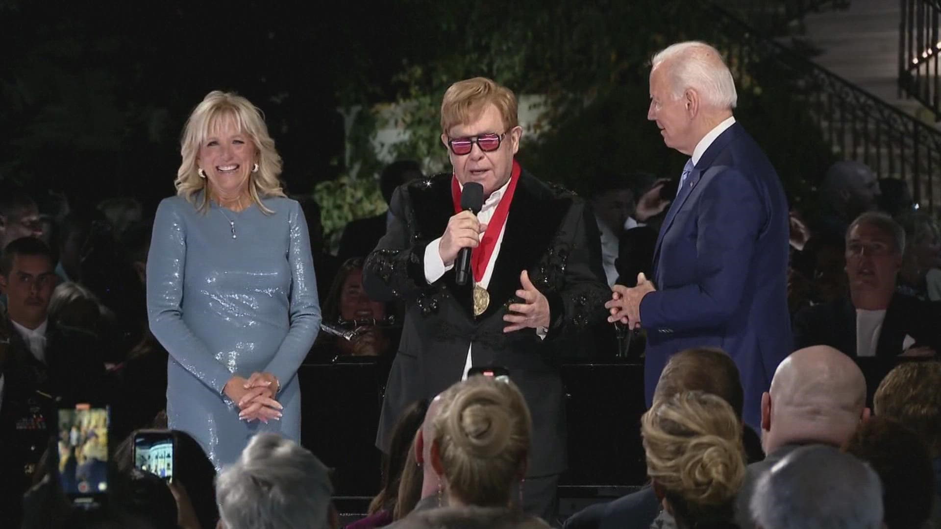 President Joe Biden surprised Elton John with the National Humanities Medal for being a “tidal wave” who helped people rise up for justice.